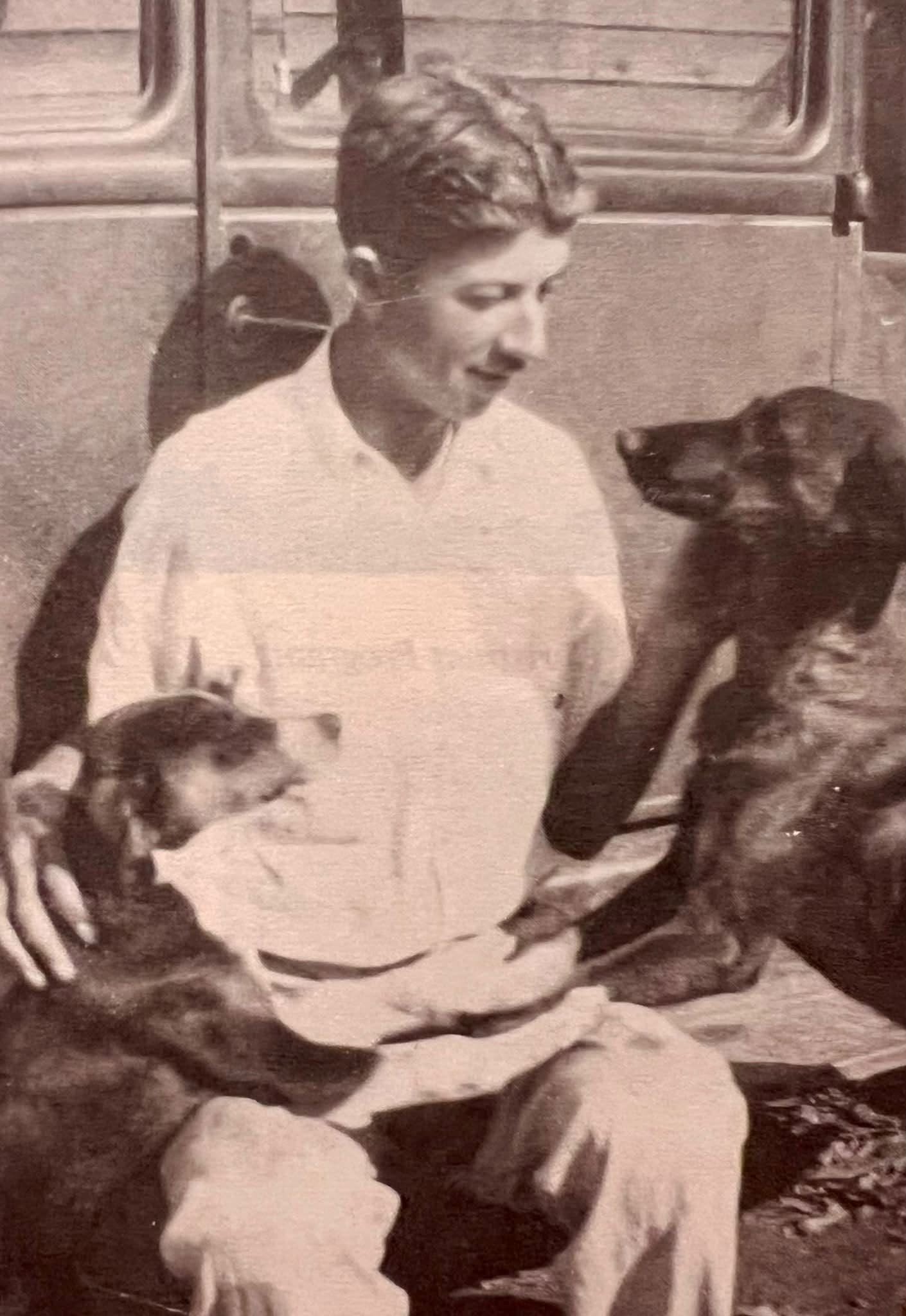 Doc Holcomb seated outdoors with his dogs in the 1930s.