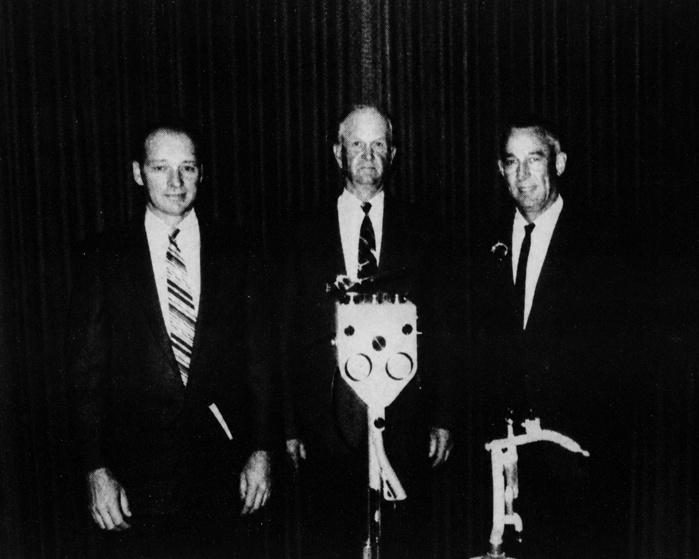 Edsel Orr, R. D. Garrett and J. M. Potts standing behind a machine in 1970.
